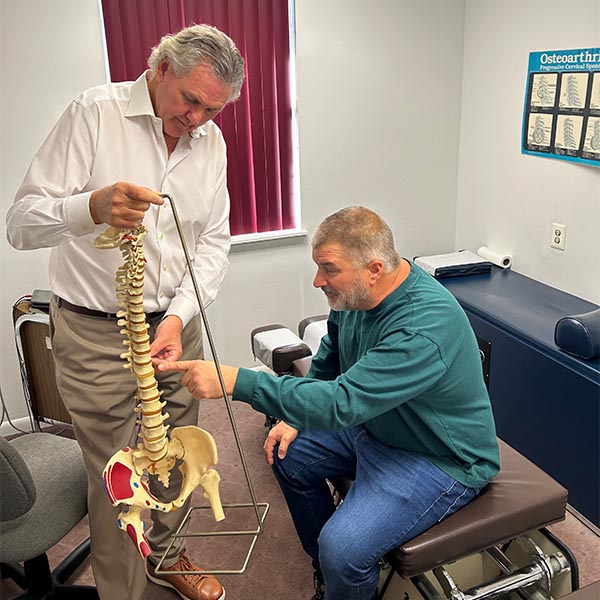 Dr. Schmetterling showing model spine to patient